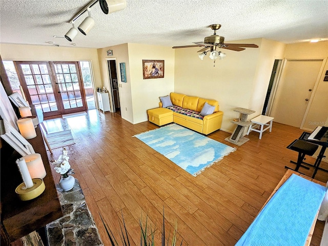 living room with wood-type flooring, track lighting, a textured ceiling, and french doors