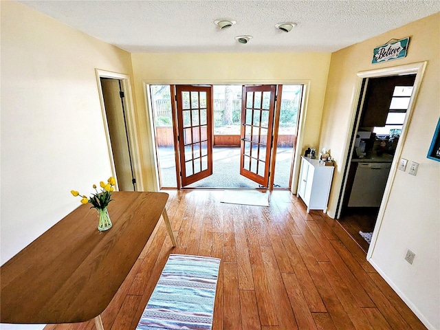 doorway with french doors, hardwood / wood-style floors, and a textured ceiling