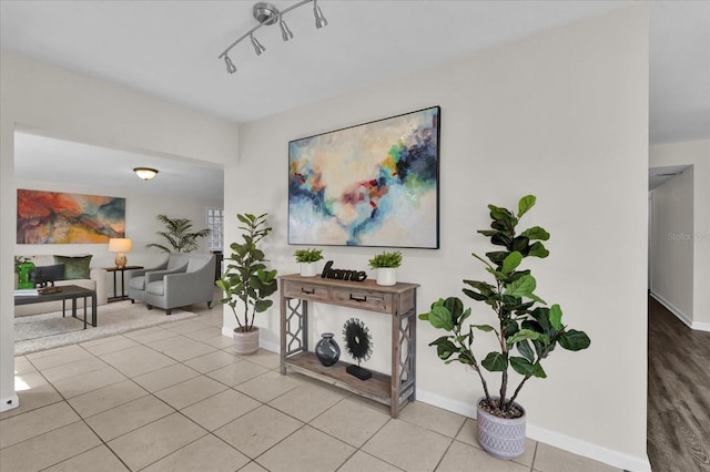 hallway featuring rail lighting and light tile patterned flooring