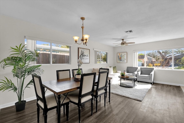 dining space featuring dark wood-type flooring and ceiling fan with notable chandelier