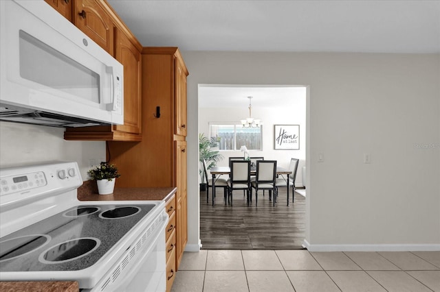 kitchen featuring pendant lighting, light tile patterned floors, white appliances, and a notable chandelier