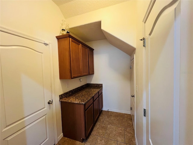 kitchen with lofted ceiling and dark stone countertops