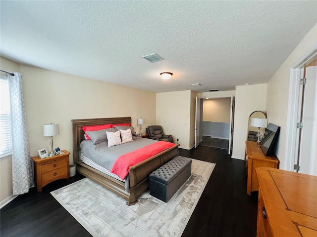 bedroom featuring a textured ceiling and dark hardwood / wood-style flooring