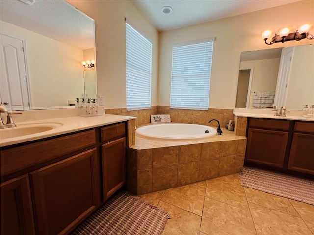 bathroom with tile patterned flooring, vanity, and tiled bath