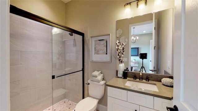 bathroom featuring vanity, a shower with shower door, and toilet