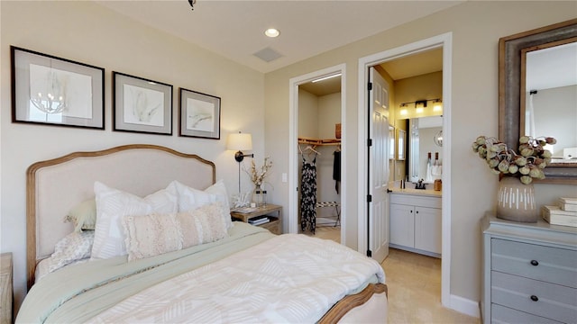 bedroom with ensuite bathroom, sink, a walk in closet, light colored carpet, and a closet