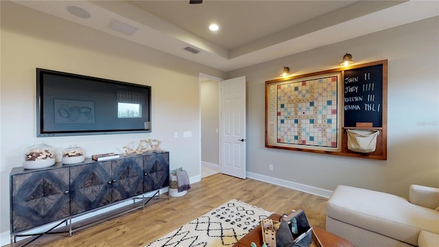 living room with a raised ceiling and light hardwood / wood-style floors