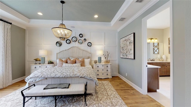 bedroom with crown molding, ensuite bath, a chandelier, light hardwood / wood-style flooring, and a raised ceiling