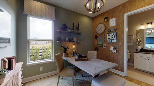 dining space with light wood-type flooring, an inviting chandelier, and sink