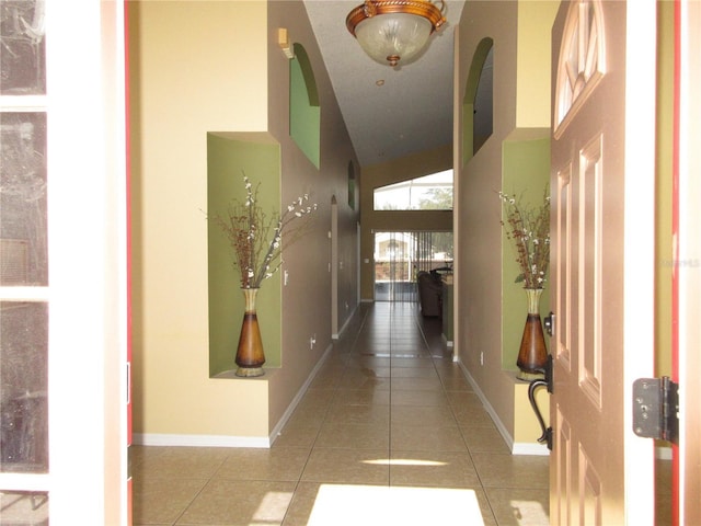 hallway featuring light tile patterned flooring and high vaulted ceiling