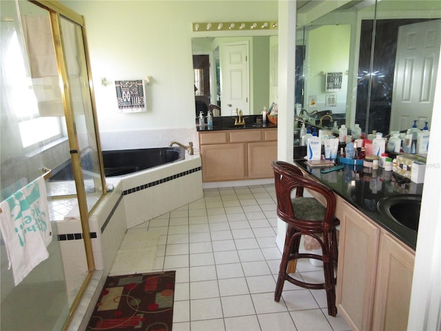 bathroom with a relaxing tiled tub, vanity, and tile patterned floors