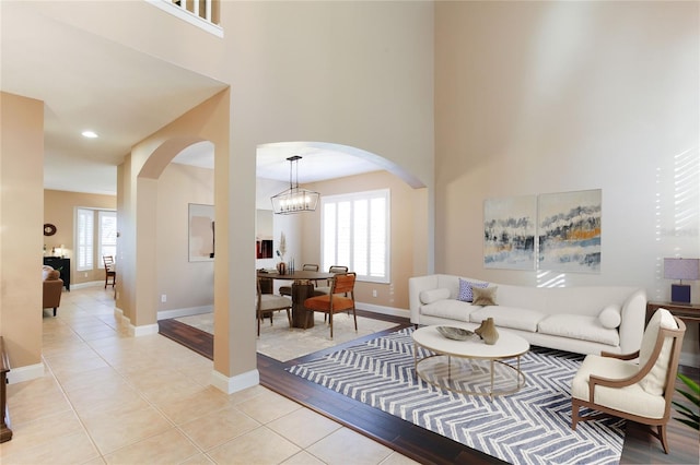 tiled living room with a high ceiling and a chandelier