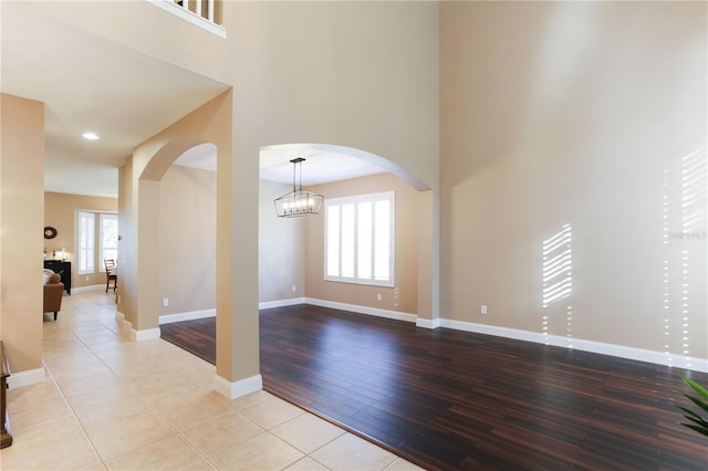 interior space with plenty of natural light, light hardwood / wood-style floors, an inviting chandelier, and a towering ceiling