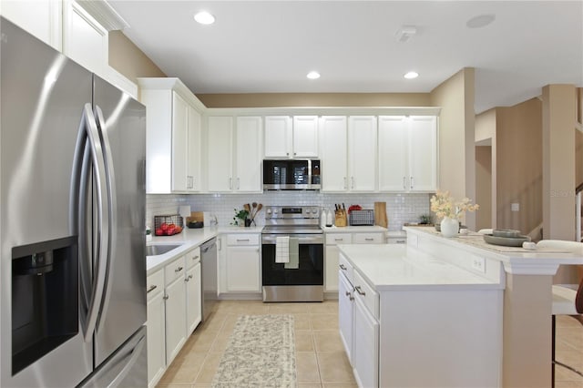 kitchen with white cabinetry, a breakfast bar, stainless steel appliances, and decorative backsplash