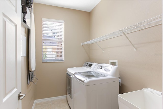 clothes washing area with light tile patterned flooring, independent washer and dryer, and sink