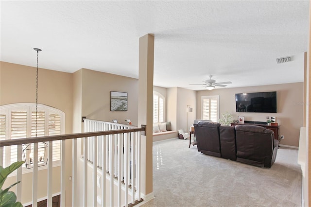 carpeted living room with a textured ceiling and ceiling fan