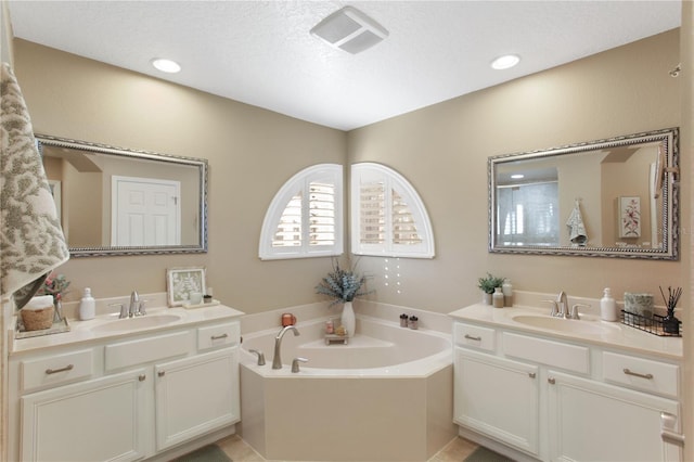 bathroom with a textured ceiling, vanity, and a washtub