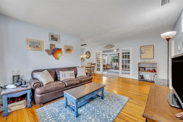 living room featuring french doors, a textured ceiling, and hardwood / wood-style flooring