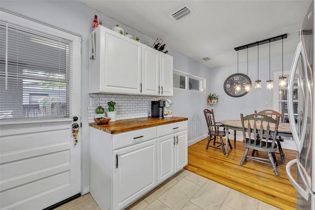 kitchen featuring wooden counters, decorative light fixtures, light tile patterned floors, decorative backsplash, and white cabinets