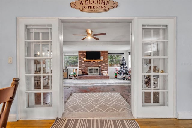 living room with ceiling fan, light hardwood / wood-style floors, and a brick fireplace