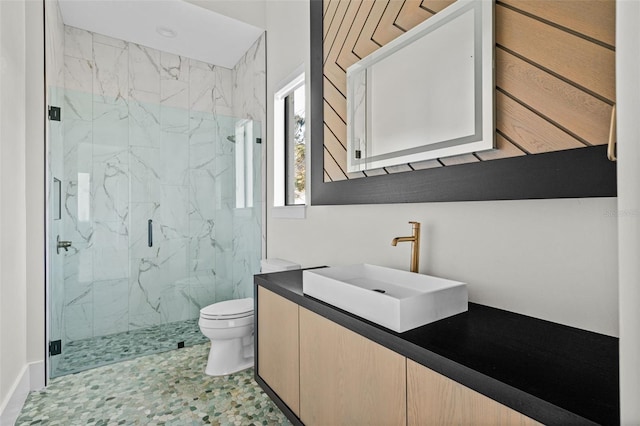 bathroom featuring toilet, a marble finish shower, and vanity