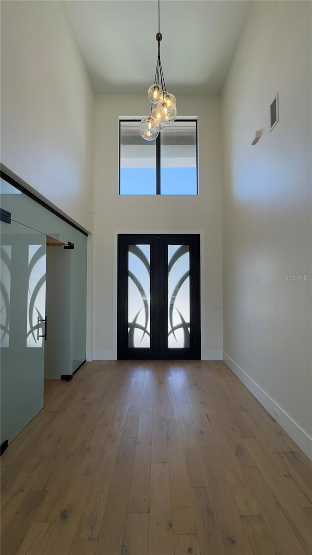 foyer entrance featuring a chandelier, visible vents, french doors, hardwood / wood-style floors, and plenty of natural light