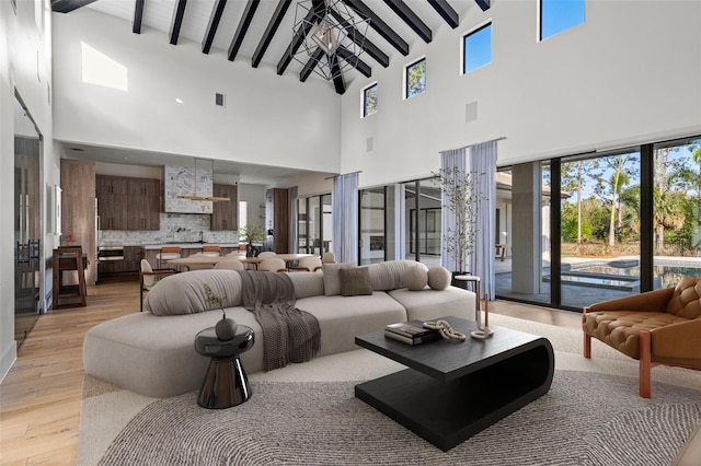 living area with beamed ceiling and light wood-style flooring