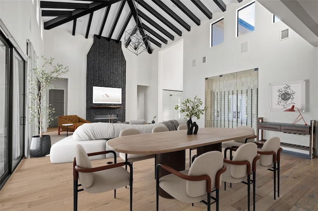 dining room with plenty of natural light, lofted ceiling with beams, light wood-type flooring, and visible vents