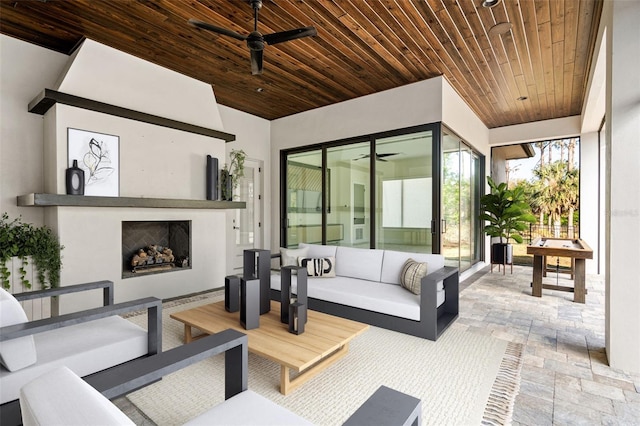 view of patio with a ceiling fan and an outdoor living space with a fireplace