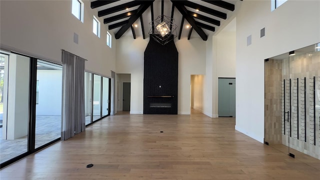 unfurnished living room with visible vents, beam ceiling, light wood-style flooring, and baseboards