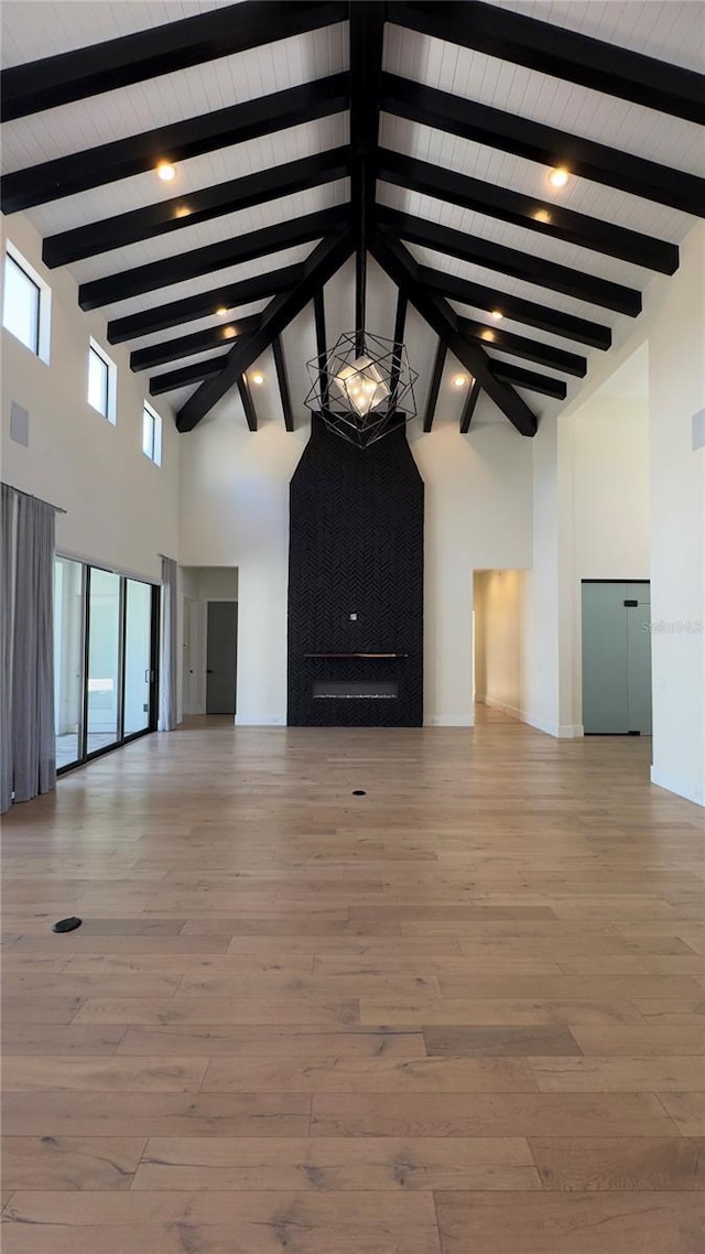 unfurnished living room with high vaulted ceiling, beamed ceiling, and light wood-type flooring