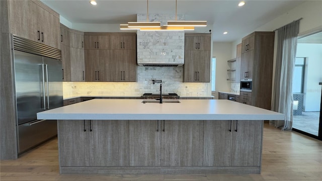 kitchen with light countertops, backsplash, light wood-style floors, modern cabinets, and built in refrigerator