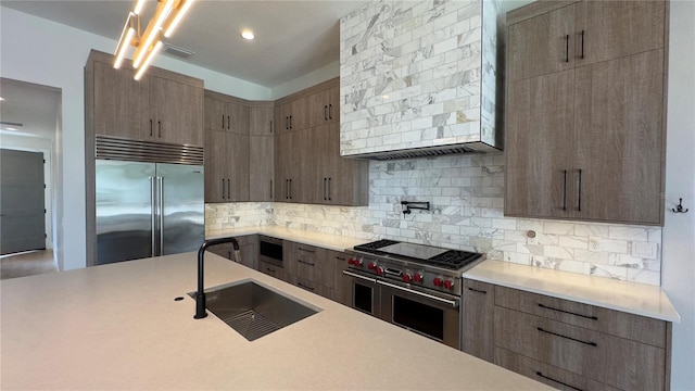 kitchen featuring light countertops, a sink, and built in appliances