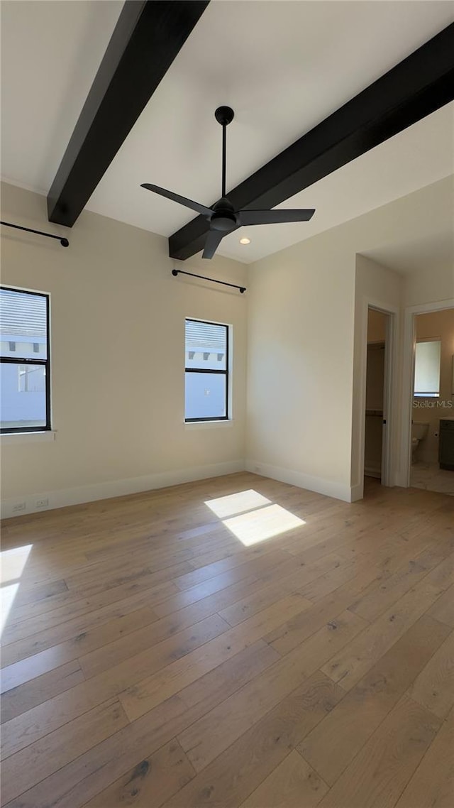 empty room featuring a ceiling fan, light wood-type flooring, beamed ceiling, and baseboards