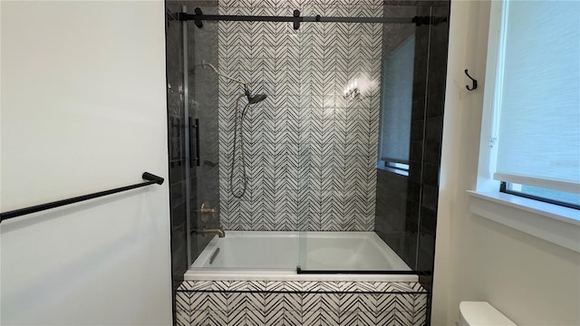 full bathroom featuring tiled shower / bath combo and toilet