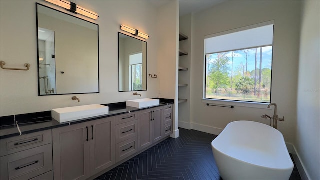 bathroom featuring a freestanding bath, double vanity, a sink, and baseboards