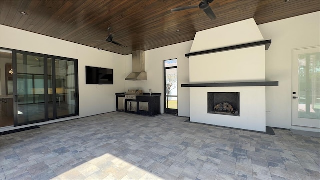 view of patio featuring a ceiling fan, a large fireplace, area for grilling, and an outdoor kitchen