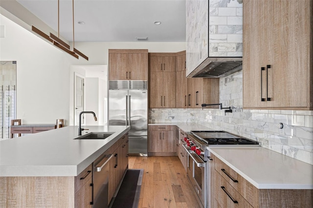 kitchen with high end appliances, light countertops, a sink, and decorative backsplash