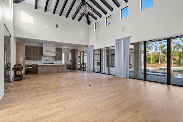 unfurnished living room with beam ceiling, visible vents, and light wood-style flooring