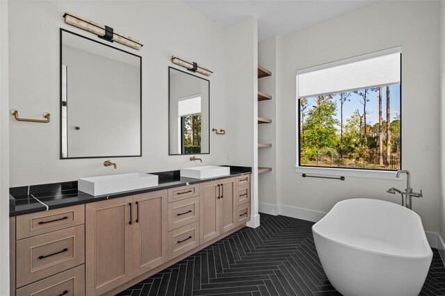 full bath featuring a soaking tub, a sink, baseboards, and double vanity