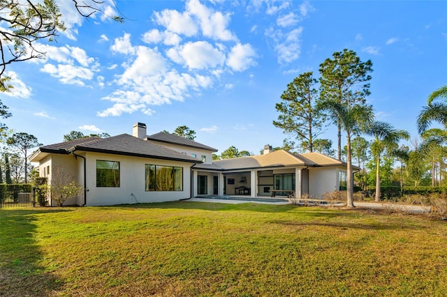 rear view of house featuring a chimney, a lawn, fence, and a patio