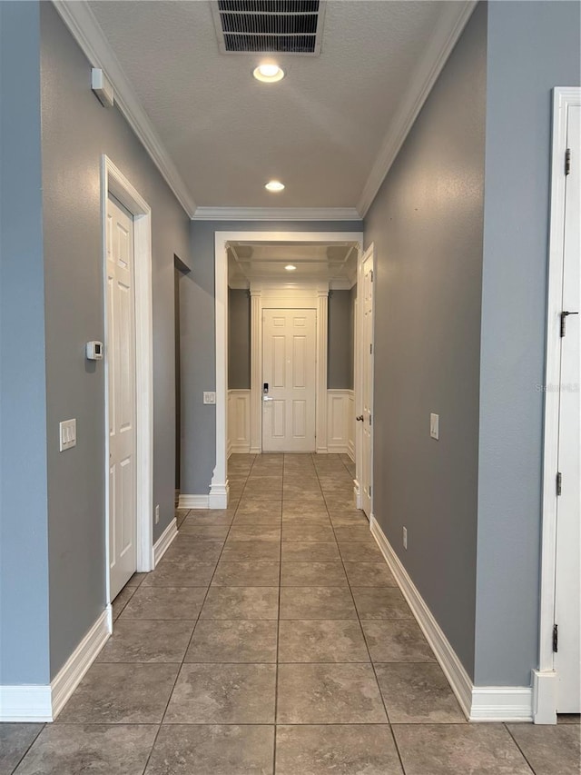 hallway featuring dark tile patterned floors and ornamental molding