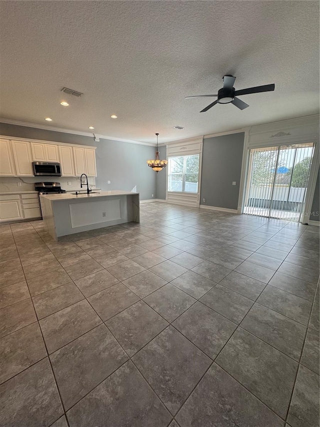 kitchen with sink, stainless steel appliances, ornamental molding, white cabinets, and a center island with sink