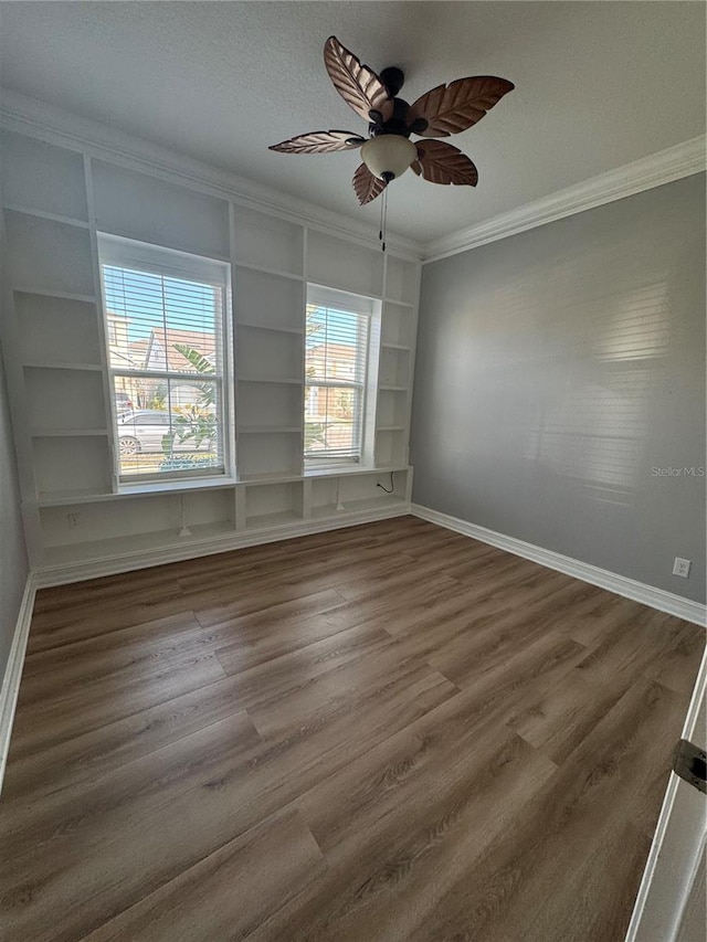 spare room with ornamental molding, dark wood-type flooring, ceiling fan, and built in shelves