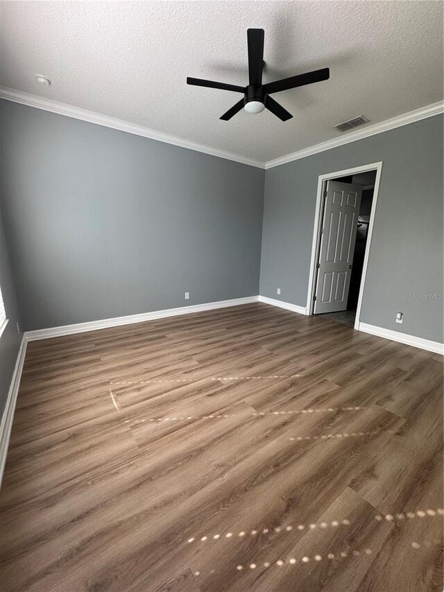 empty room featuring wood-type flooring, ornamental molding, and a textured ceiling