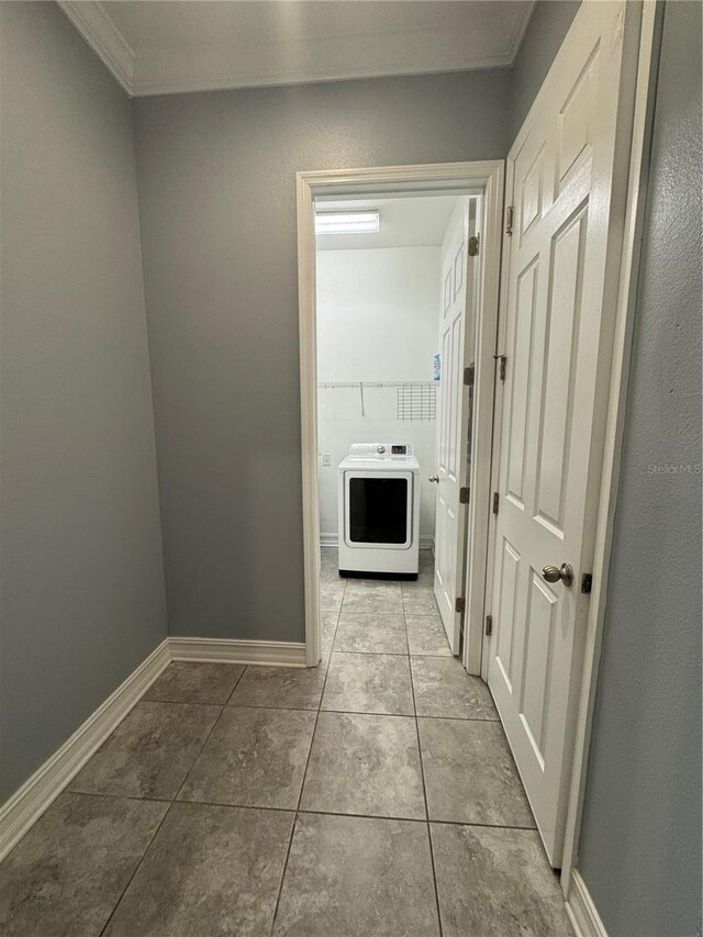 corridor with light tile patterned flooring, washer / dryer, and ornamental molding