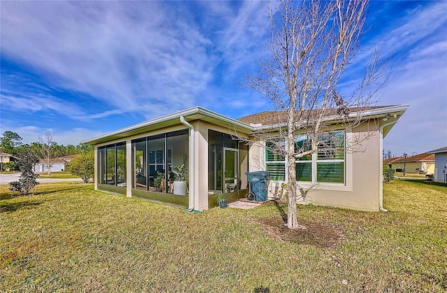 back of house featuring a sunroom and a lawn