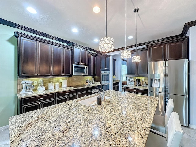 kitchen featuring appliances with stainless steel finishes, decorative light fixtures, light stone countertops, and sink