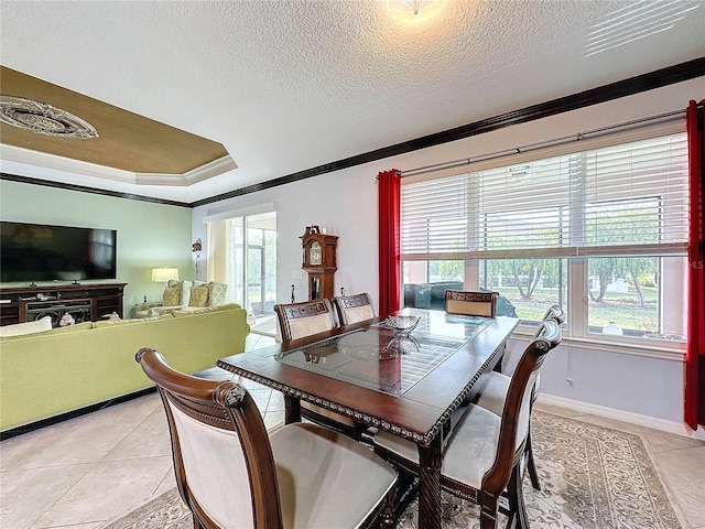 tiled dining area featuring crown molding, a tray ceiling, and a textured ceiling