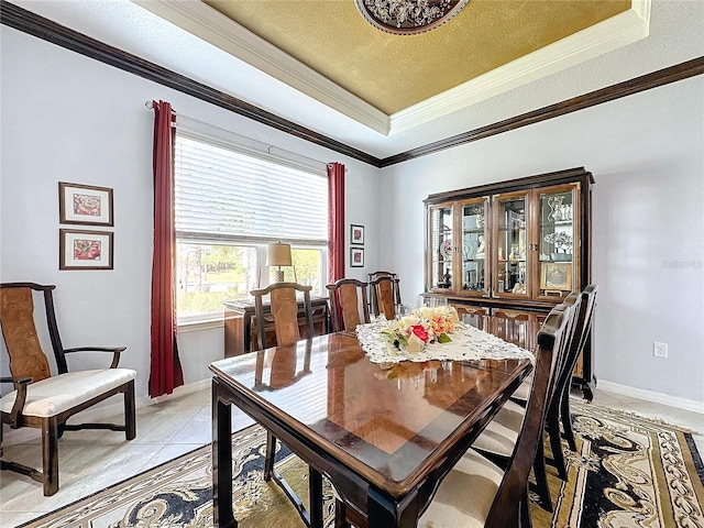 dining space with ornamental molding, light tile patterned floors, a textured ceiling, and a tray ceiling